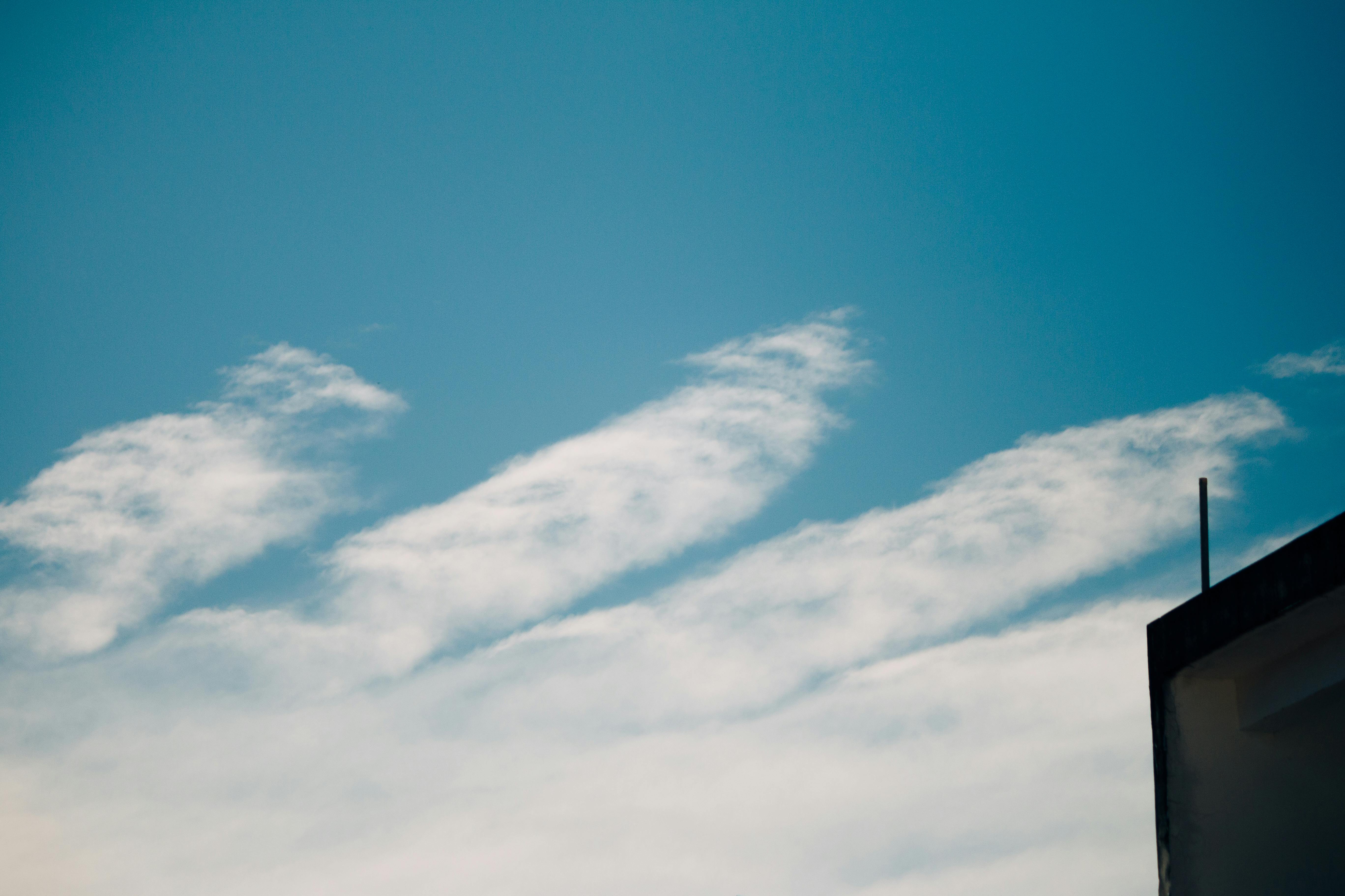 Free Clear blue sky with wispy clouds and a building corner, perfect for background use. Stock Photo