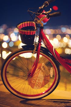 夜晚，一辆配有篮子的红色自行车，在模糊的城市灯光映衬下，展现出充满活力的城市生活方式