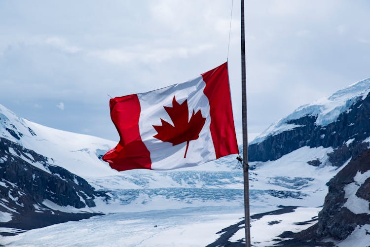 Canada Flag At A Pole On Mountain Area