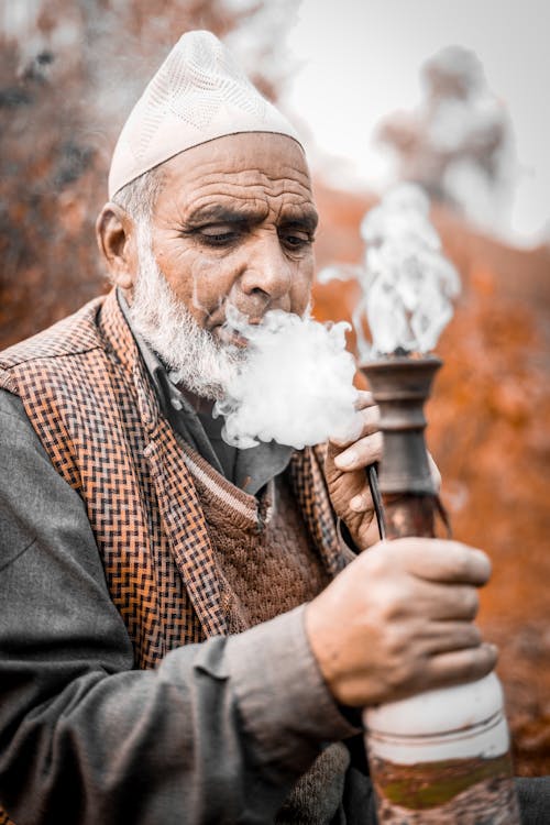 Free Man Wearing a Kufi Hat Smoking Shisha Stock Photo