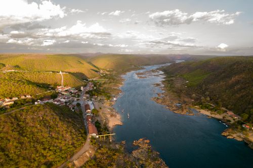 Free A breathtaking aerial view showcasing Piranhas City and the serene São Francisco River surrounded by lush hills. Stock Photo