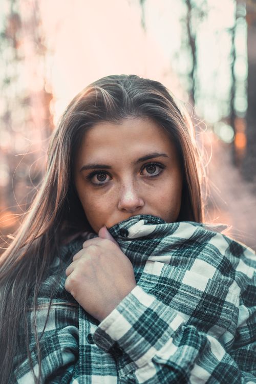 Free Close-up portrait of a young woman in a plaid shirt outdoors, showcasing a pensive expression. Stock Photo
