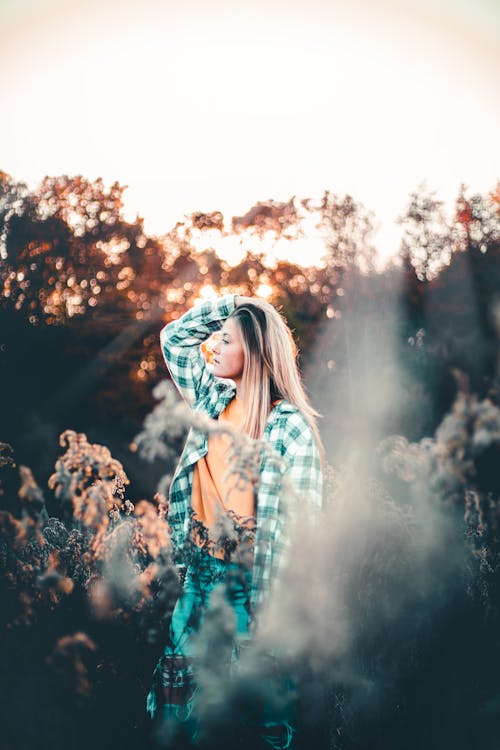 Photo of a Woman in a Plaid Shirt Posing with Her Hand on Her Head