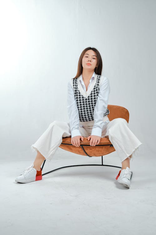 Woman in White Blazer Sitting on Brown Chair