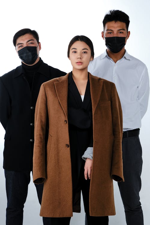 Free Men Wearing Face Masks Standing Behind a Woman Stock Photo