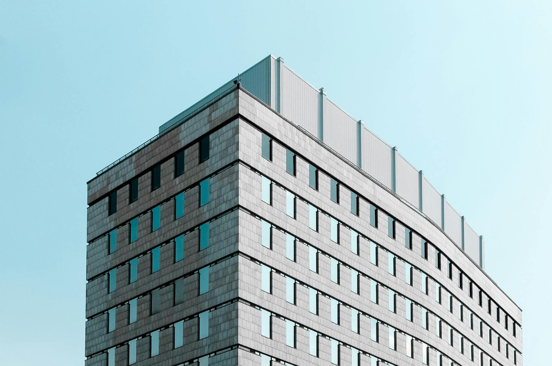 Side view of a modern office building with glass windows under a clear blue sky in urban London, Ontario.