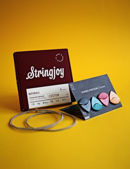 Free Guitar strings and picks displayed against a vibrant yellow background. Stock Photo