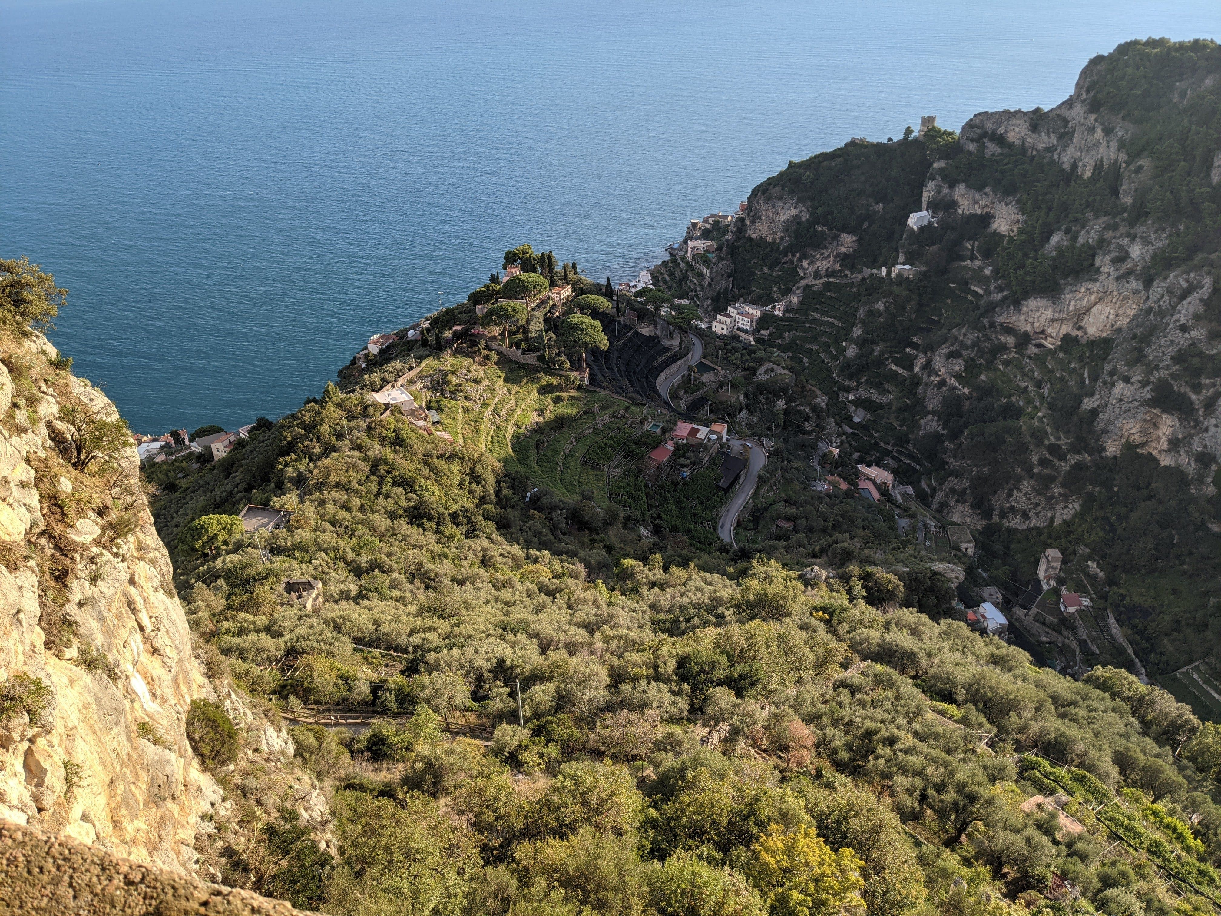 High-angle view of a picturesque coastal village nestled in lush greenery and cliffs.