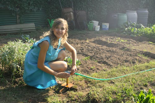 Foto Mujer Sosteniendo Una Manguera De Jardín Verde