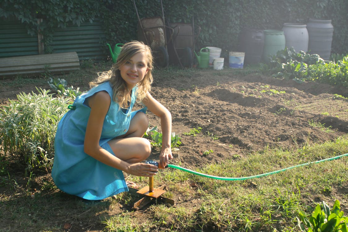 A woman fixing a water hose in a garden