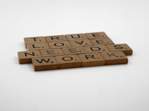 Close-Up Shot of Scrabble Tiles on White Surface