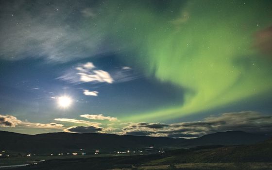 Spectacular Northern Lights display above Iceland's dark landscape with a starry night sky.