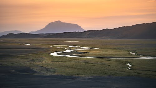 Brown Mountain and Green Grass Field during Sunset