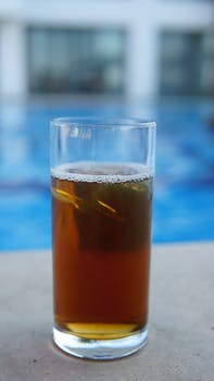 Glass of iced tea by the pool, offering a refreshing summer drink experience.