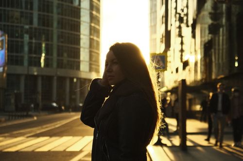 Free Backlit view of a woman crossing a street in Moscow, Russia, during sunset with tall buildings around. Stock Photo