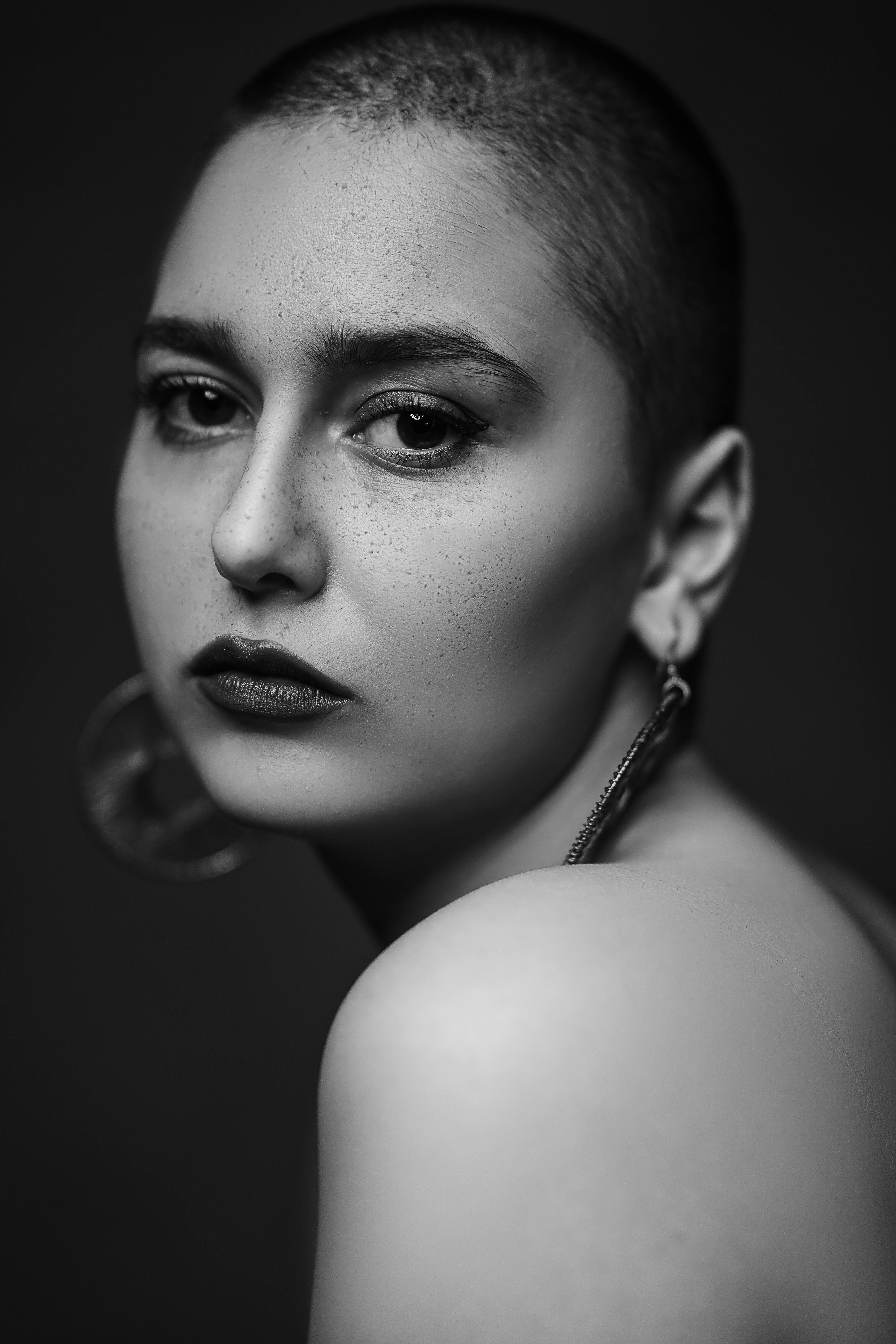 Intense black and white portrait of a woman with earrings and make-up, showcasing emotion.