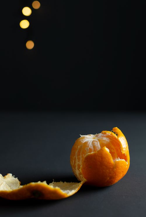 Free A creatively peeled tangerine against a dark background with bokeh lights. Stock Photo
