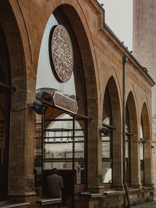 Free Exterior view of a historic mosque with arched architecture and sign featuring intricate calligraphy. Stock Photo