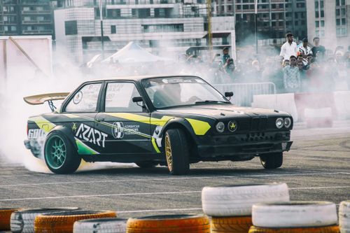 Free Dynamic car drifting scene with a crowd of spectators in an outdoor event setting. Stock Photo