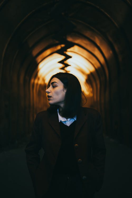 A Profile View of a Young Female in a Corridor with a Light in the Background 