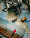 Camera, Batteries and Photographs Lying on Map