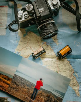 A vintage camera with film rolls on a map, featuring a photograph of a landscape scene.