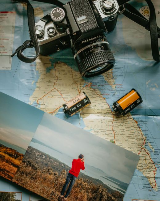 A vintage camera with film rolls on a map, featuring a photograph of a landscape scene.