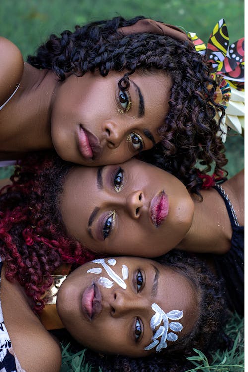 A Headshot of Three Females Laying in Vertical Position 