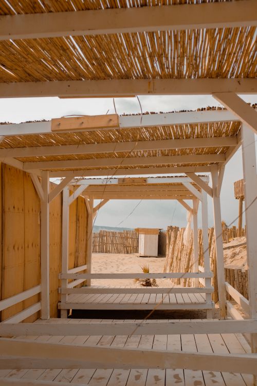 Free A rustic wooden cabana on a sandy beach, perfect for summer relaxation. Stock Photo