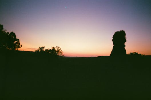 Peaceful silhouette at sunset with vibrant horizon colors in a natural setting.