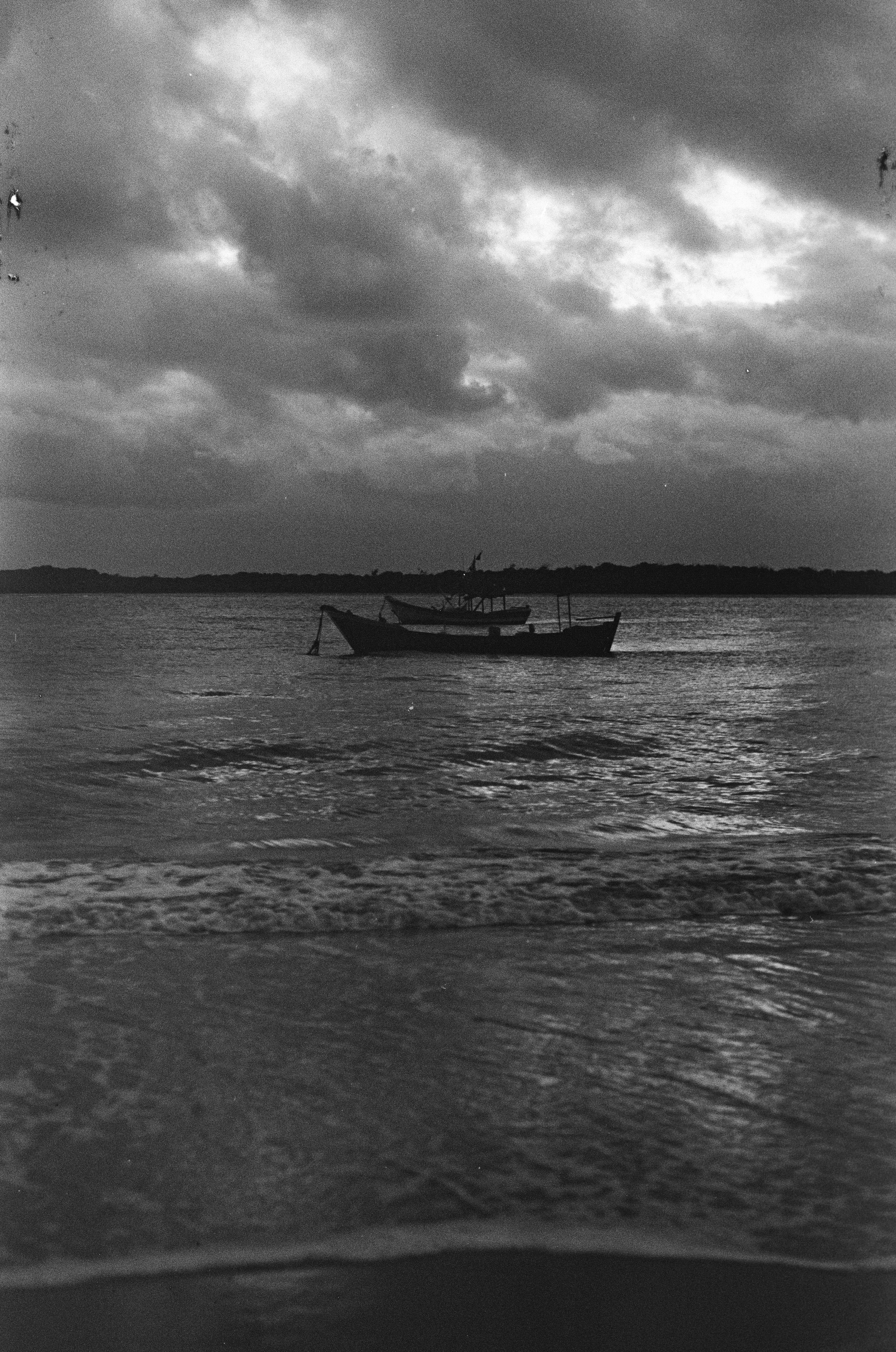 A solitary boat floats on the ocean under dramatic, cloudy skies at Superagui, Brazil.