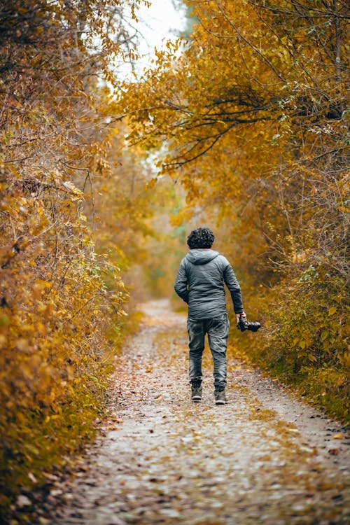 Man Holding Camera While Walking on Path