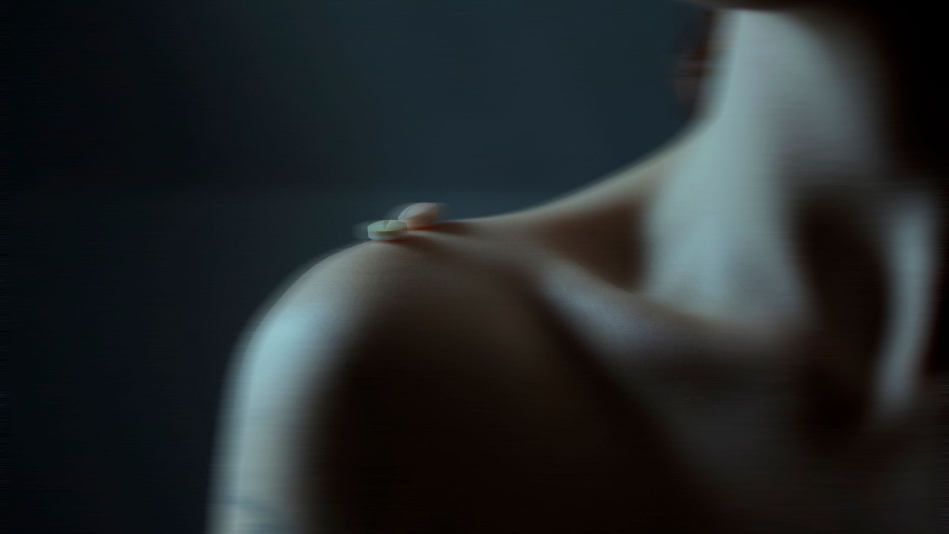 Blurry artistic image of tablets on a person's shoulder, emphasizing mood.