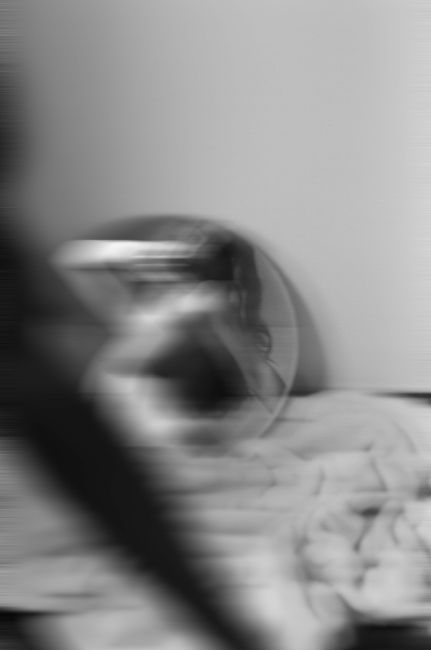 Abstract black and white motion blur image featuring a person and round mirror, creating a mysterious atmosphere.