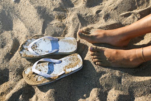 Free Photography of a Girl's Feet Near Flip-flops Stock Photo