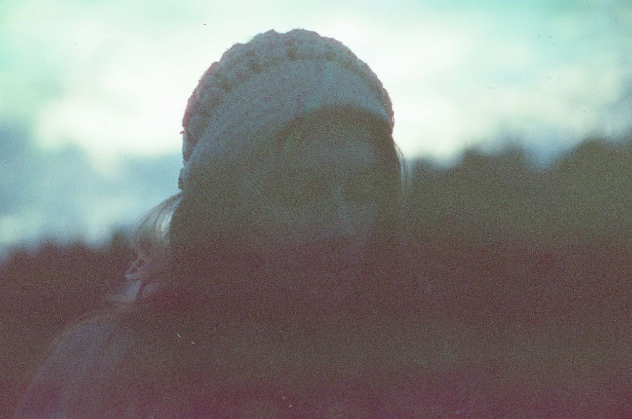 silhouetted portrait of a woman in a beanie blurred outdoors with soft