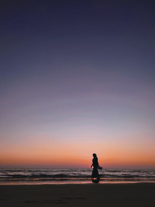 Free A serene silhouette of a person walking along a beach during twilight in Bangladesh. Stock Photo
