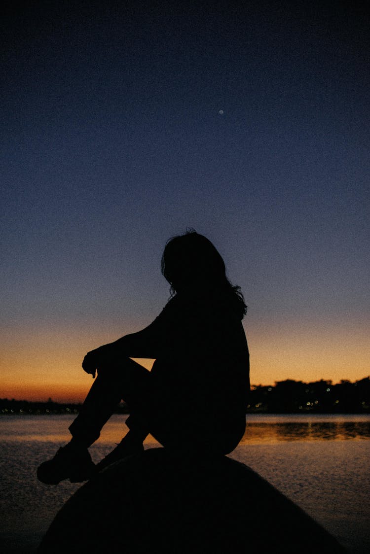 Silhouette Of Sitting Woman At Sunset