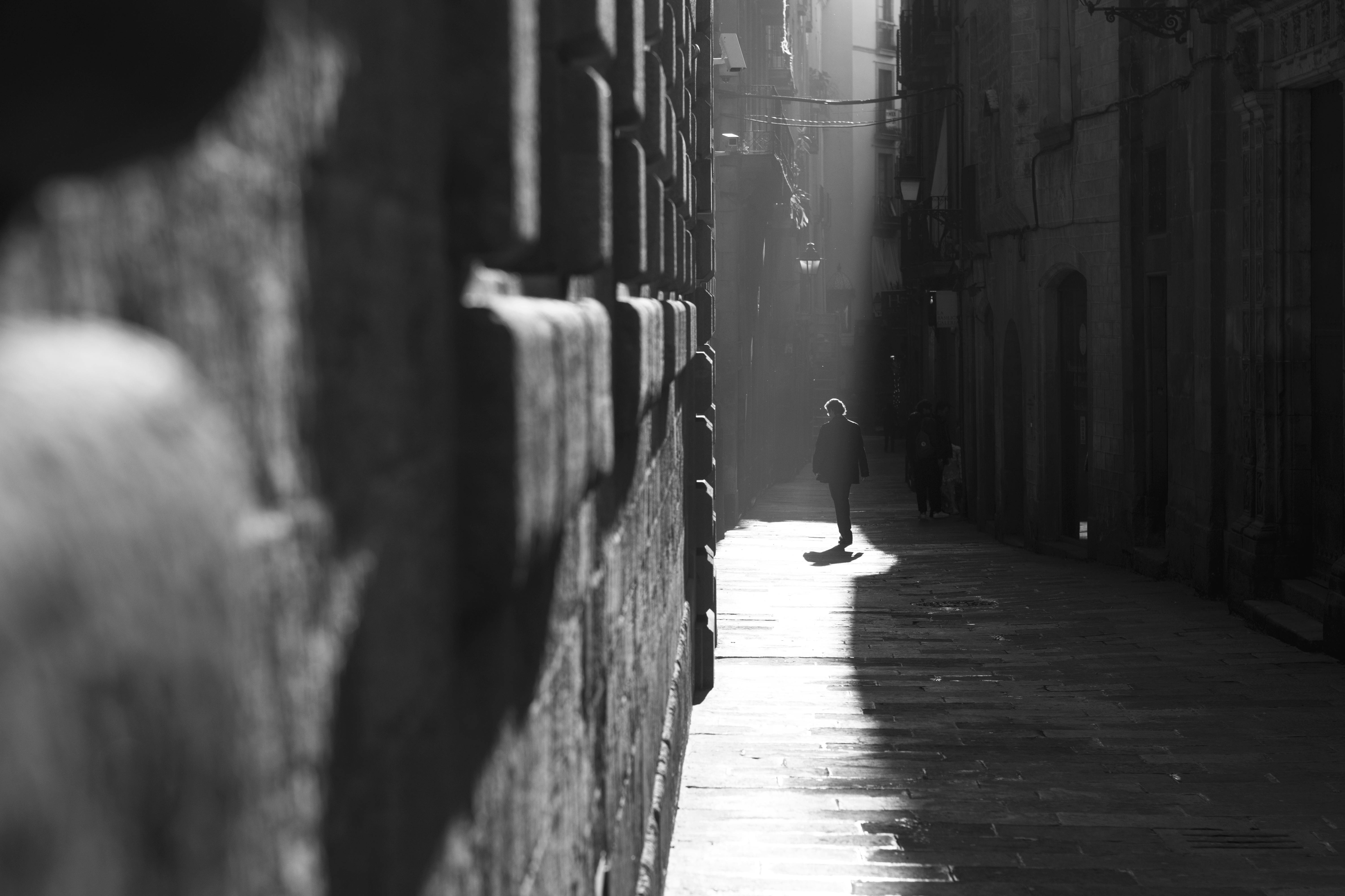 person walking in alley in grayscale photography