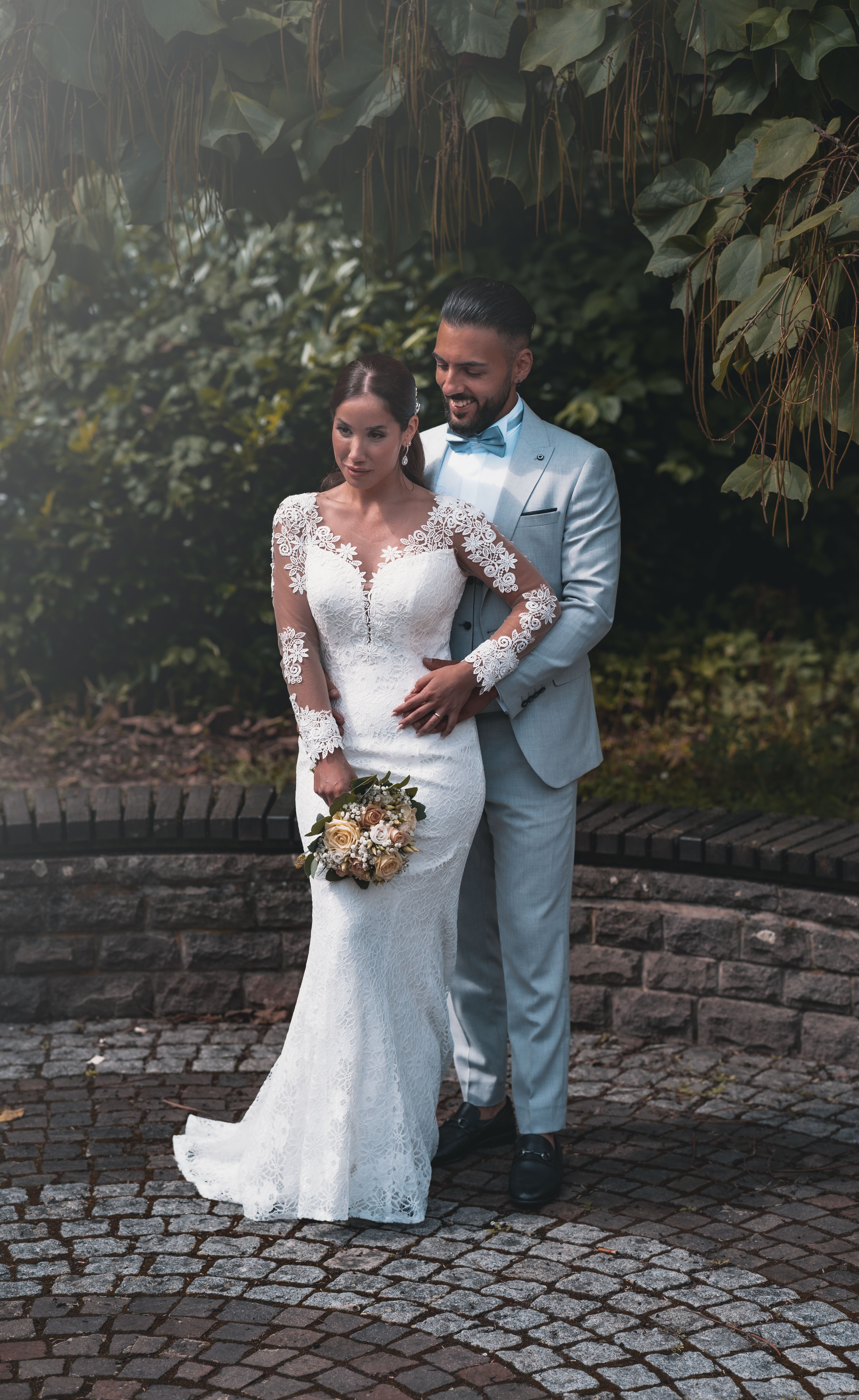 A beautiful bride and groom embrace in an outdoor garden setting.