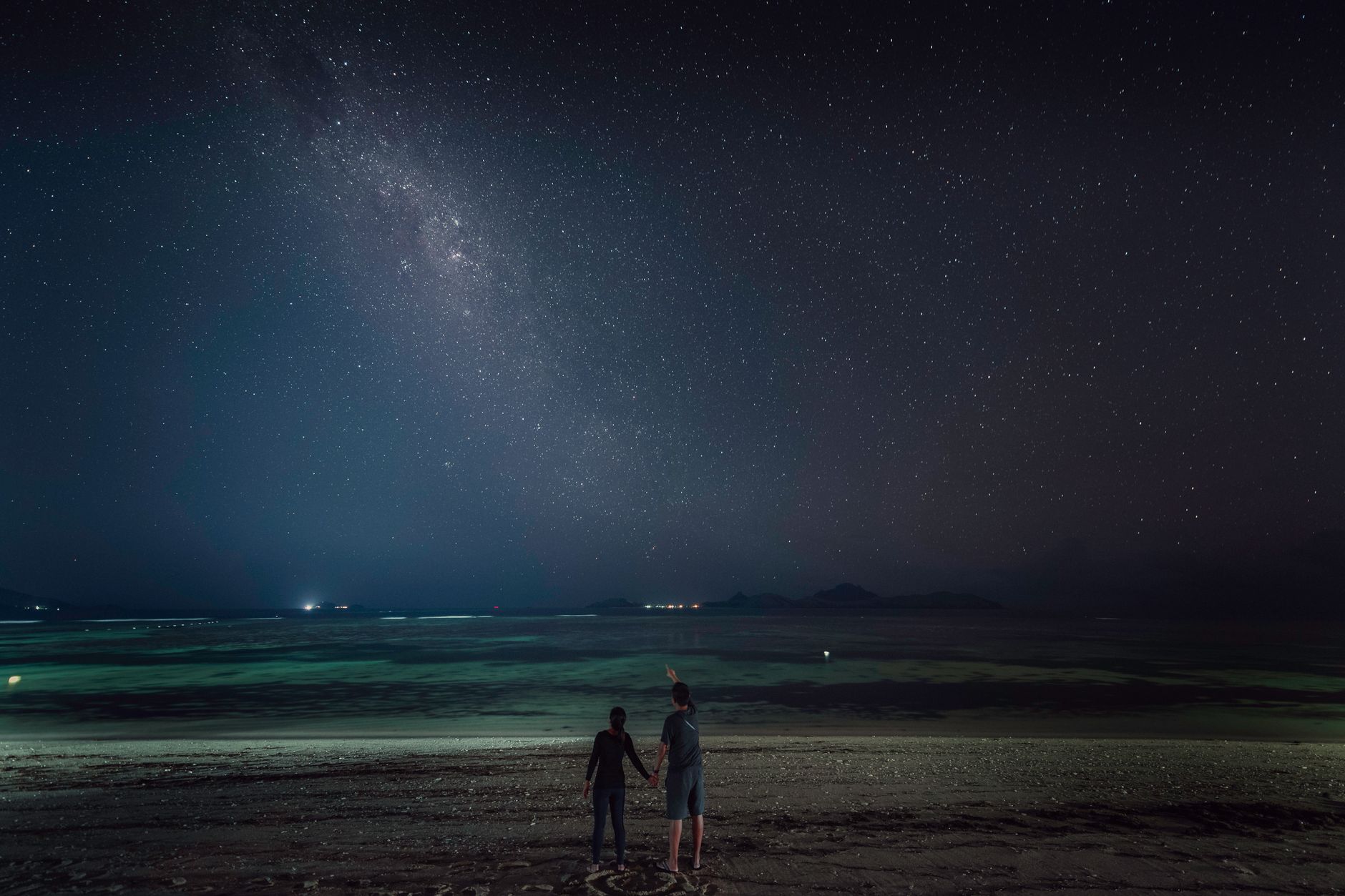 澎湖看星星約會景點(夜晚靜謐天幕的角落,最新推薦與私密地點) Romantic couple holding hands while observing stars on a beach at night