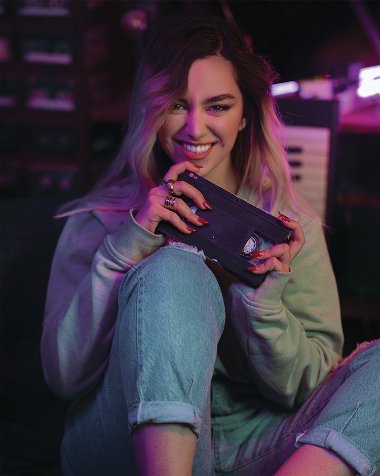 A Woman In Gray Sweater Holding A Vhs Tape