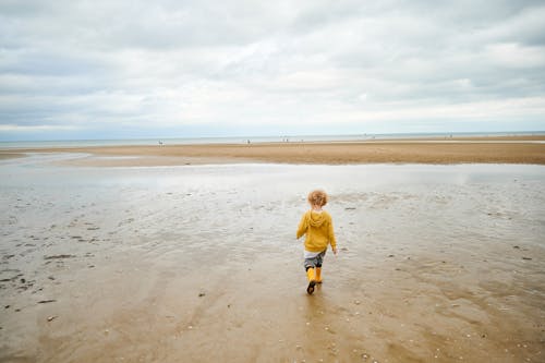 Boy in Yellow Shirt Walking on Brown Sand