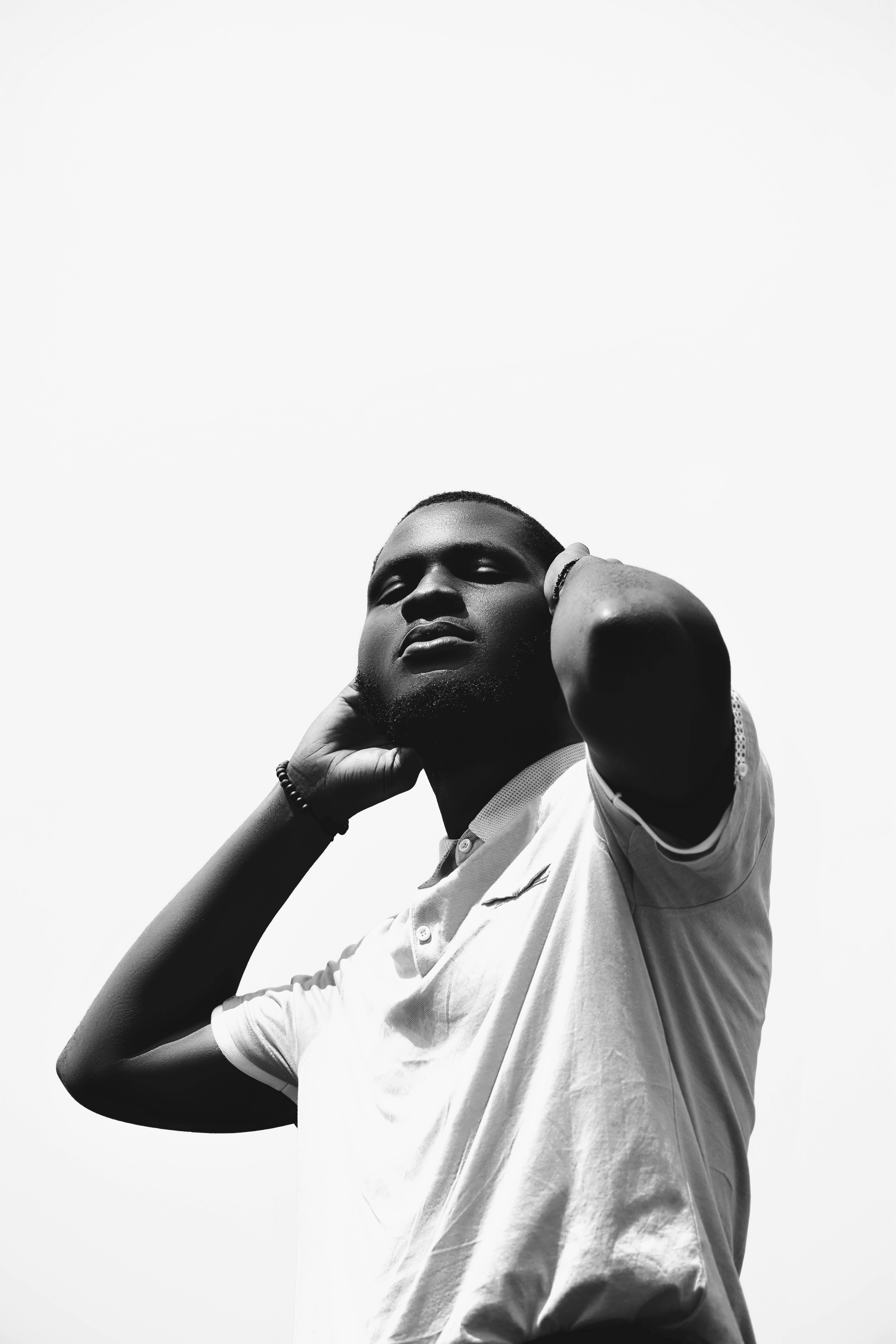 Stylish black and white portrait of a man with arms raised and head tilted back.