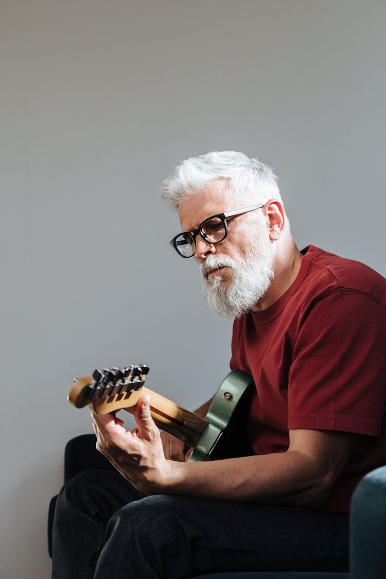 Elderly Man Tuning Electric Guitar