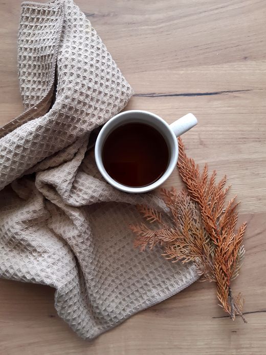 Taupe waffle weave towel beside a mug of tea and dried branch