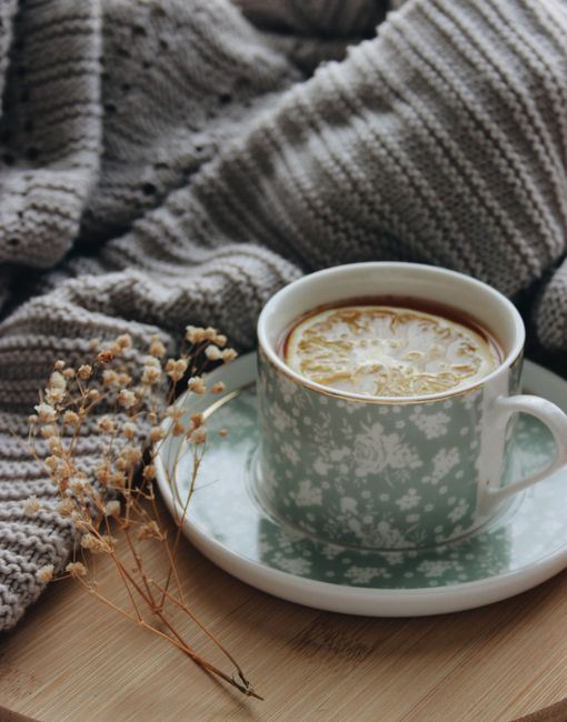 A warm cup of tea with a lemon slice in a floral cup, perfect for a cozy day indoors.