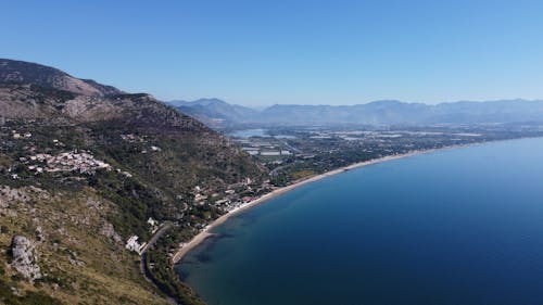 An Aerial Photography of a Beach Near the Mountain Under the Blue Sky