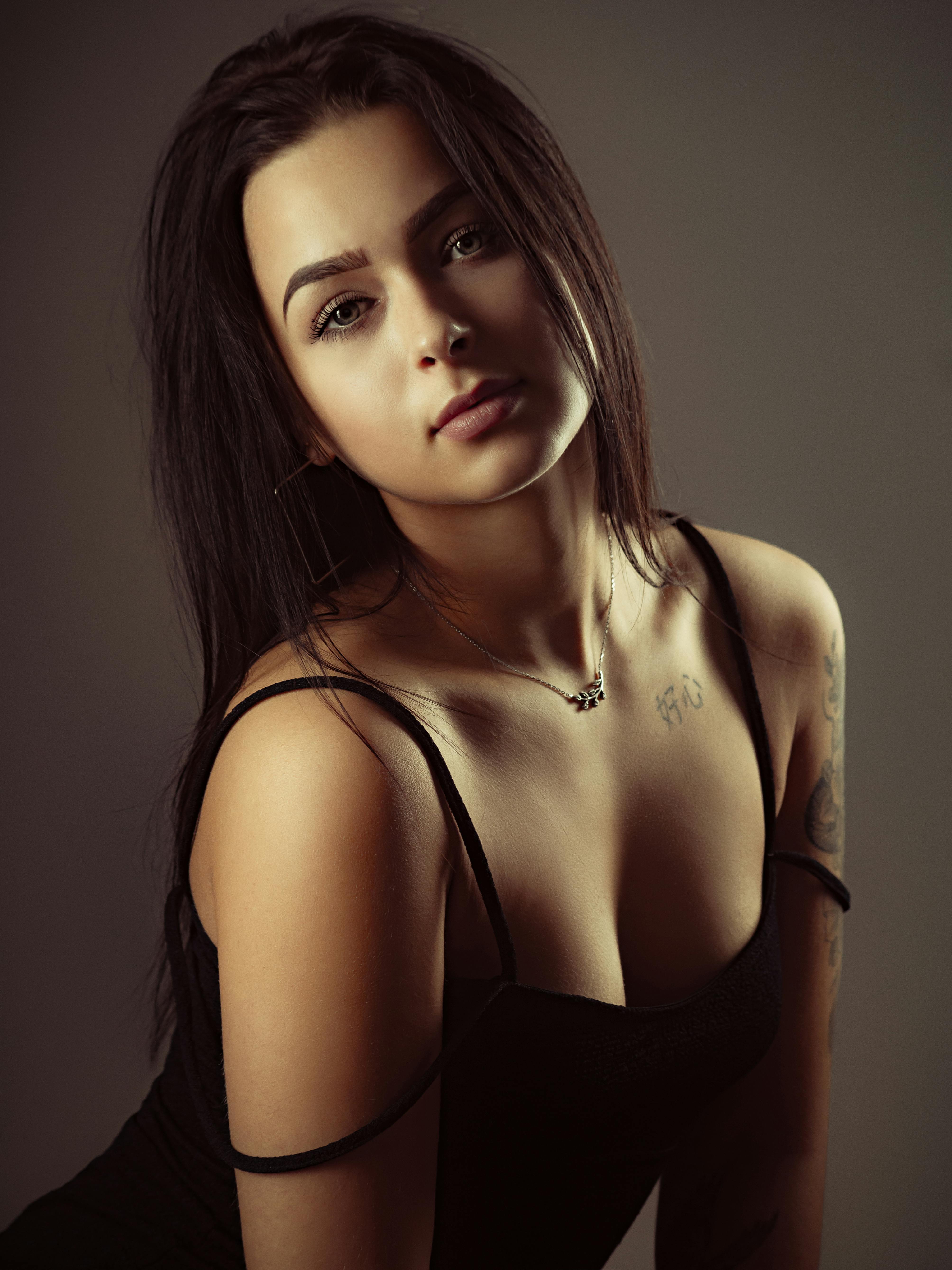 Captivating studio portrait of a young woman with long hair and tattoos, presenting elegance and confidence.
