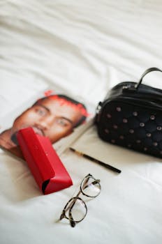 A modern arrangement of fashion and reading essentials on a bed.